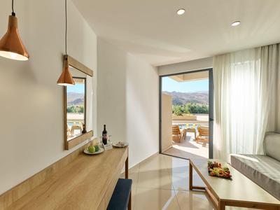 Helles Hotelzimmer mit Terrasse, Blick auf Berge und moderner Einrichtung in Holz und Weiß.