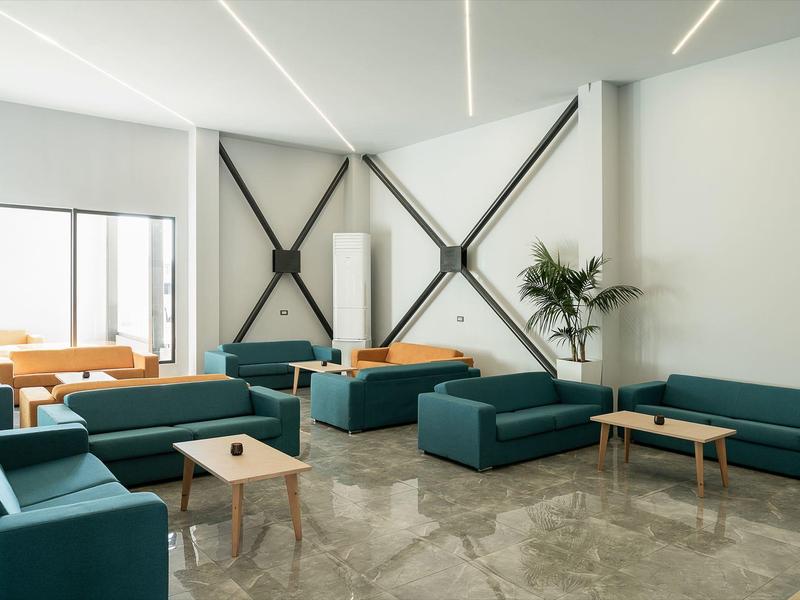 Moderne lounge met blauwe sofa's, houten tafels en minimalistisch wit wandontwerp.