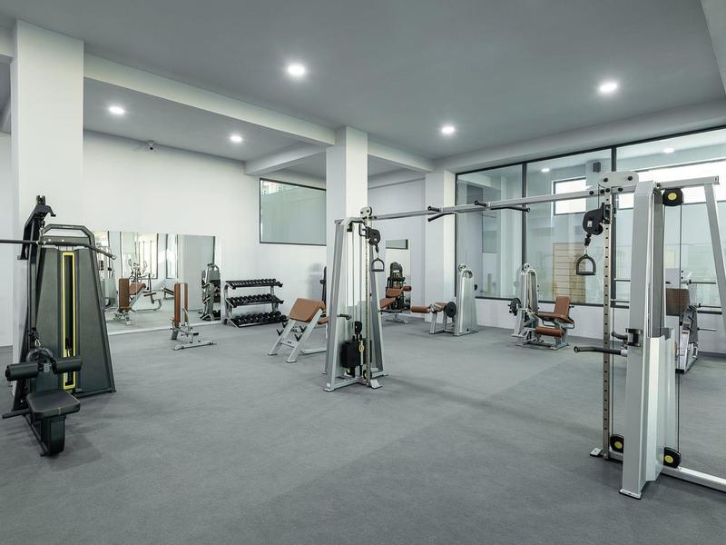 Moderne fitnessruimte met verschillende trainingsapparaten en grijs tapijt.