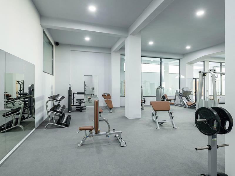 Moderne fitnessruimte met diverse trainingsapparatuur en een spiegelwand.