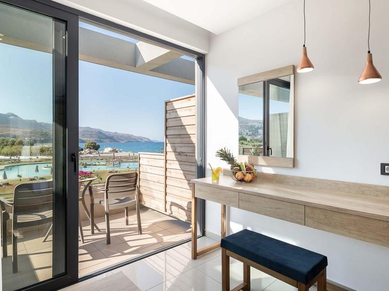 Moderne hotelkamer met kaptafel en balkon met zeezicht en zitgelegenheid.