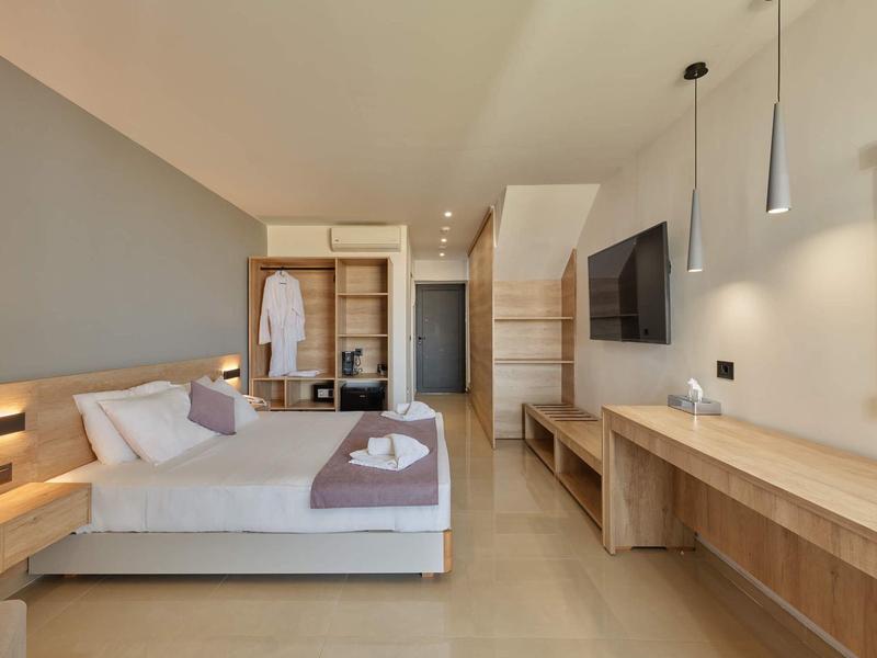 Moderne hotelkamer met tweepersoonsbed, grote spiegel, houten meubels en neutrale kleuren.