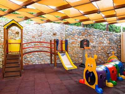 Colorful children's playground with slide and ladybug crawl tunnel under yellow sunshade.