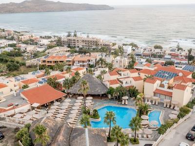 View of a hotel resort with pool, sun umbrellas, and a sea with an island in the background.