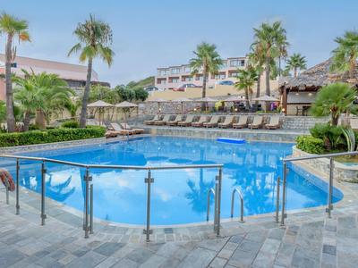 Moderner poolbereich mit Palmen, Liegestühlen und Sicht auf mehrstöckiges Hotelgebäude.