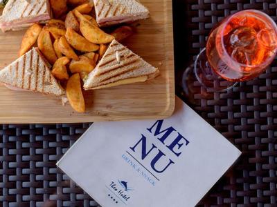 Tray with sandwiches and fries next to a drink and a menu on a table.
