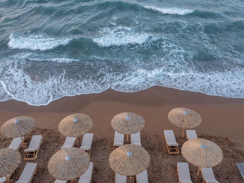 Aerial view of a sandy beach with umbrellas and calm sea waves