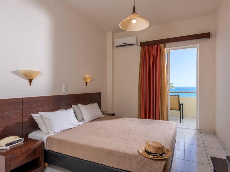 Bright hotel room with double bed, balcony, and sea view