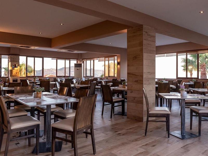 Bright, modern restaurant with wooden decor and mountain views at sunset.