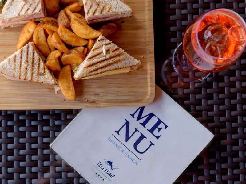Tray with sandwiches and fries next to a drink and a menu on a table.