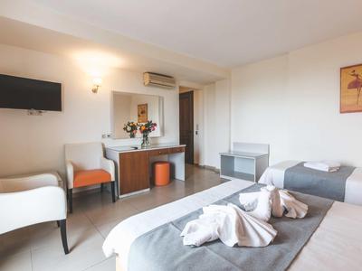 Lichte hotelkamer met twee bedden, tv, zithoek en bureau.