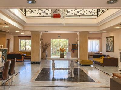 Helles Hotellobby mit glänzendem Marmorboden, Rezeption und Sitzbereichen.