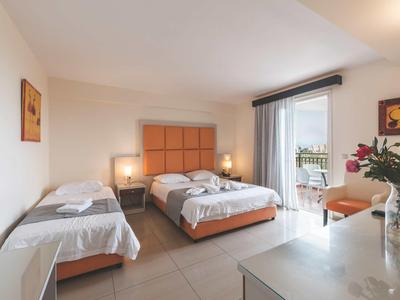 Heldere hotelkamer met drie bedden en toegang tot een balkon.