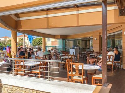 Offene Hotelterrasse mit gedeckten Tischen und Stühlen unter einem Sonnendach.
