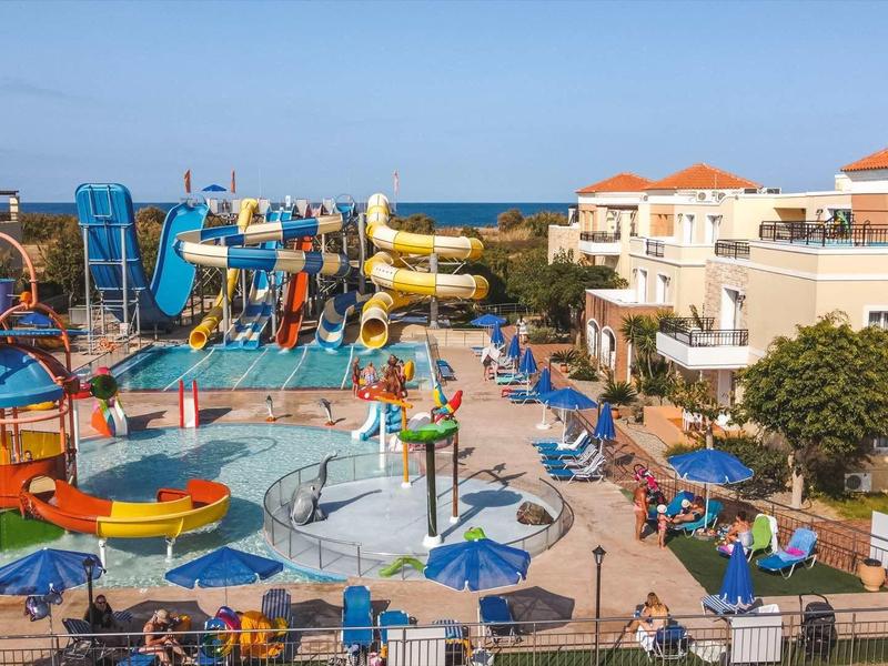 Kleurrijk waterpark met glijbanen en zwembaden in een hotelcomplex bij zonnig weer.