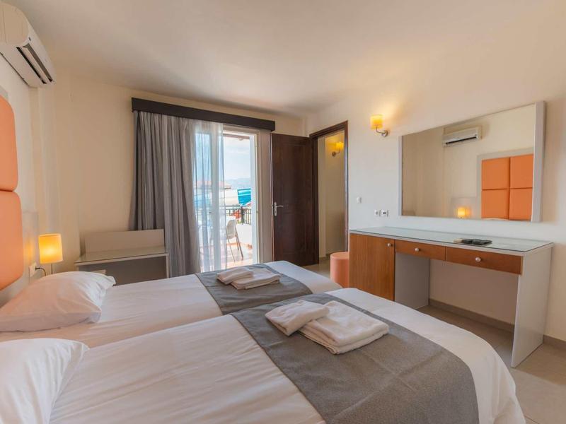 Modern hotelkamer met twee eenpersoonsbedden, balkon en minimalistisch interieur.