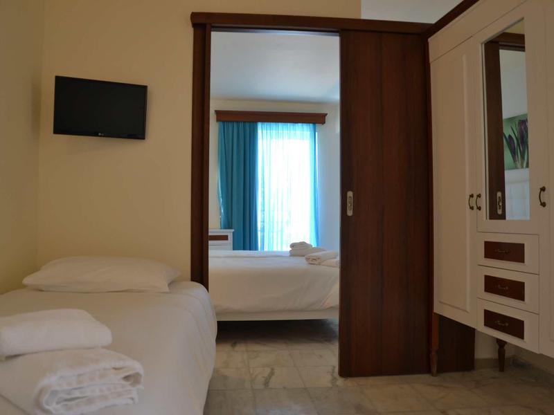 Een hotelkamer met twee bedden, een kledingkast en een kleine tv aan de muur.