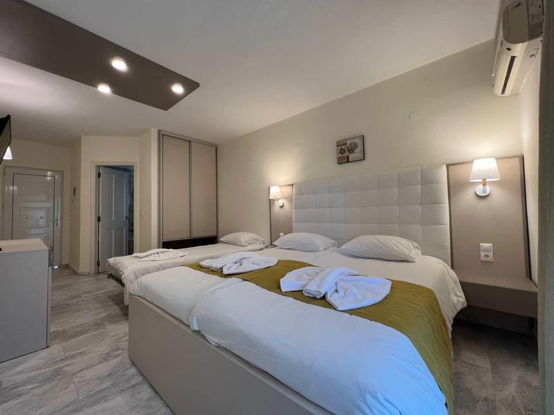 Moderne hotelkamer met twee bedden, wit hoofdeinde en minimalistische verlichting.