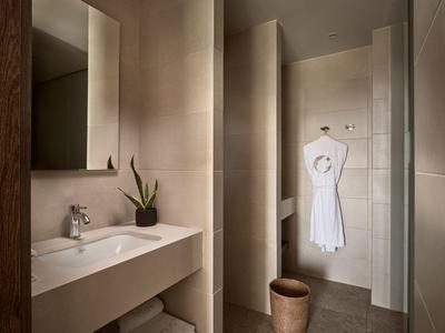 Salle de bain moderne avec lavabo, grand miroir et peignoir accroché à la porte.