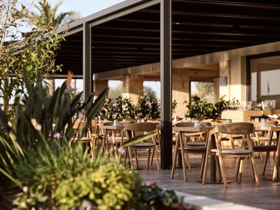 Restaurant extérieur couvert et chaleureux avec tables et chaises en bois dans un cadre naturel.