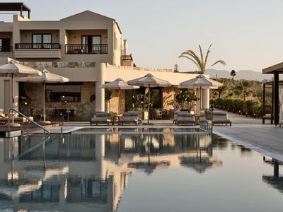 Moderner Hotelpoolbereich mit Sonnenliegen und Sonnenschirmen bei Sonnenuntergang.