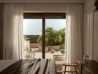 Chambre avec accès ouvert à une terrasse avec plantes et sièges.