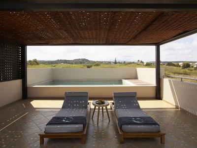 Terrasse couverte avec deux chaises longues et une petite table donnant sur le paysage.