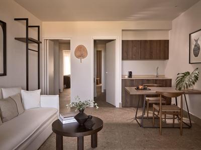 Salon moderne avec canapé, petite table et cuisine attenante.