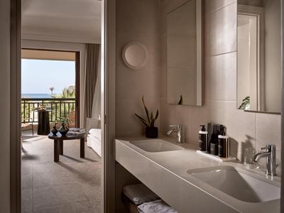 Chambre d'hôtel moderne avec salle de bain, balcon et vue sur la mer.