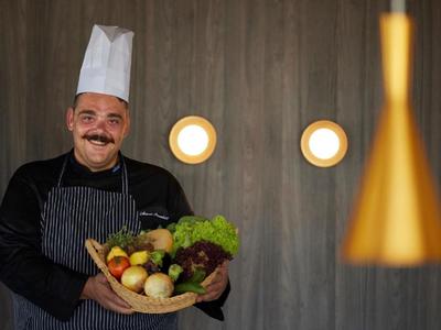 Chef tient un panier de légumes frais devant un fond moderne.