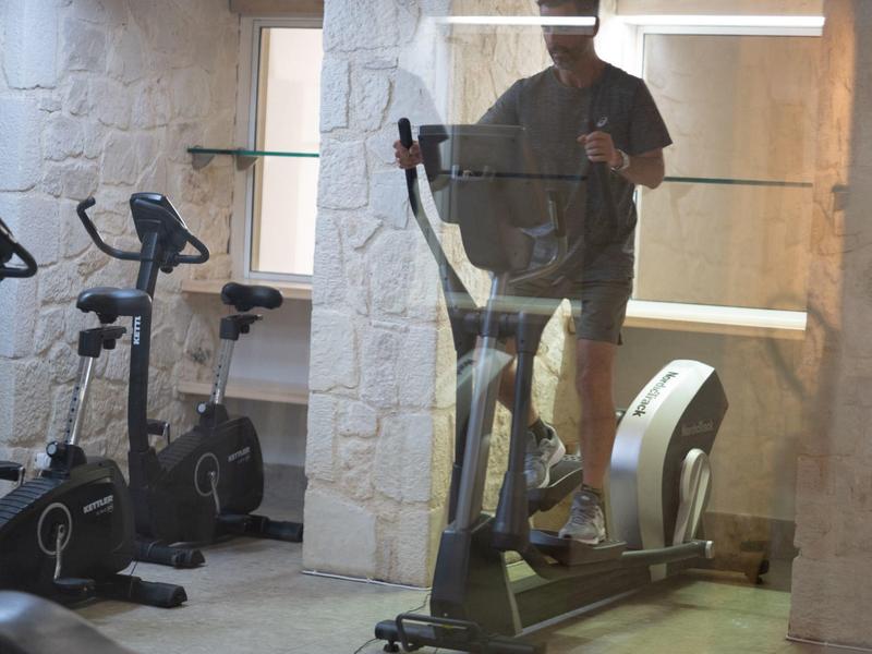 Personne fait de l'exercice sur un elliptique dans une salle de sport avec mur en pierre.