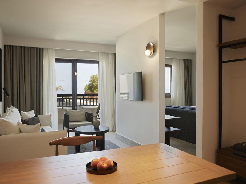 Chambre d'hôtel lumineuse avec canapé, balcon et décor minimaliste.