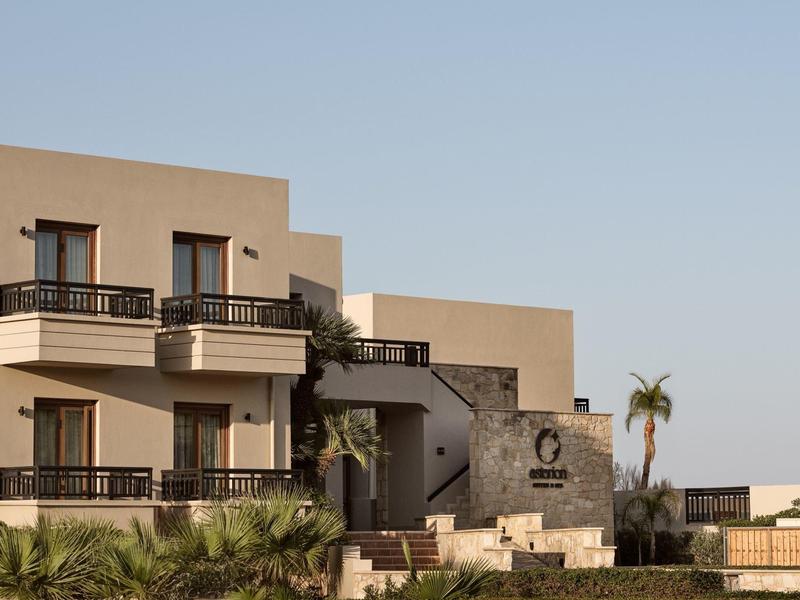 Complexe de bâtiments modernes à plusieurs étages avec balcons et palmiers au premier plan.