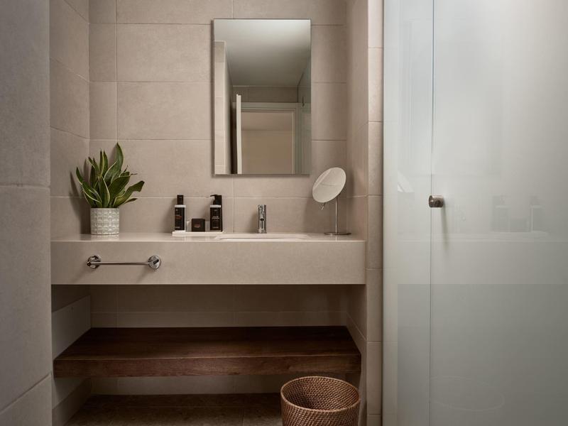 Salle de bain moderne avec lavabo, miroir et plantes aux tons neutres.