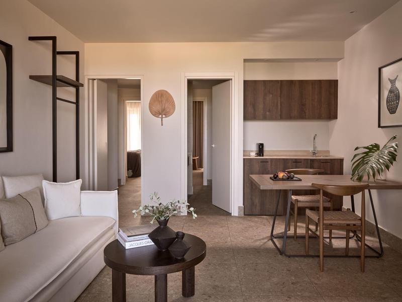 Salon moderne avec canapé, petite table et cuisine attenante.