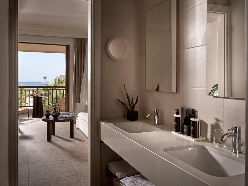 Chambre d'hôtel moderne avec salle de bain, balcon et vue sur la mer.