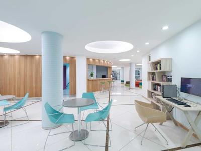 Modern bright lounge with white walls, blue chairs, and computer desks.