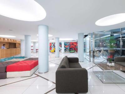 Modern hotel lobby with white walls, gray furniture, and colorful wall art.