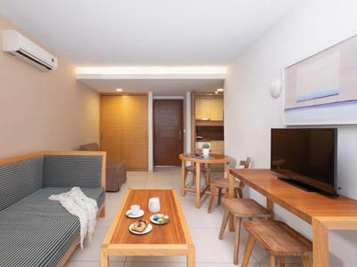 Modern hotel room with sofa, TV, dining table, and stylish lighting.