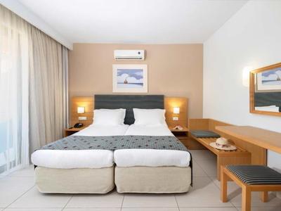 Bright hotel room with two beds, bedside lamps, and desk with mirror.