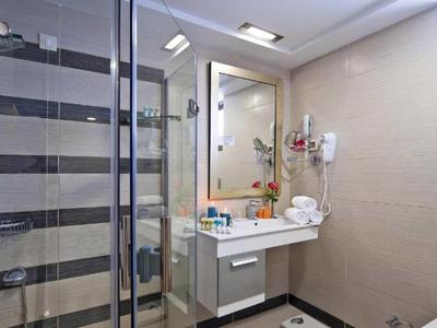 Modern bathroom with glass shower cabin, sink, and large mirror in hotel suite.