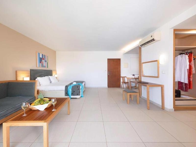 Bright hotel room with seating area, king-size bed, and desk with mirror.