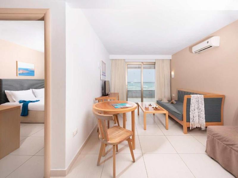 Bright living room with dining table, sofa, and sea view through the window.