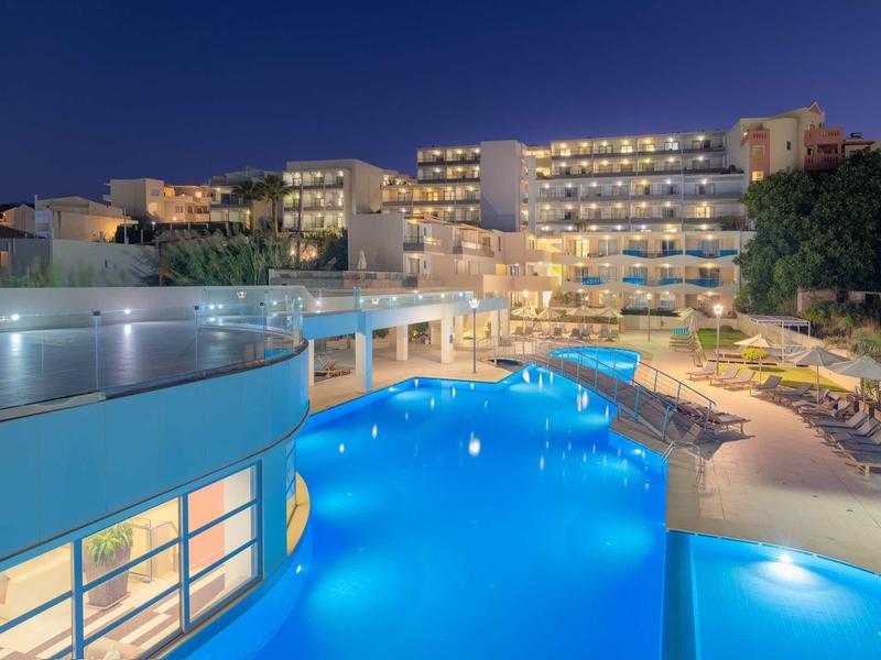 Modern hotel with illuminated pool at night and adjacent lounge seating area.