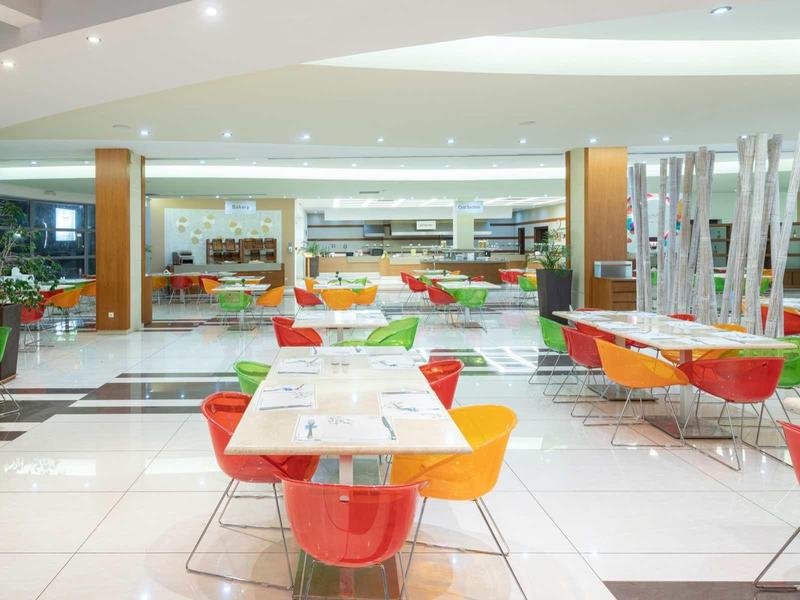 Modern dining area with colorful chairs and white tables in a hotel