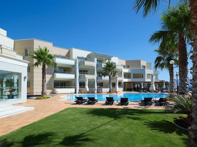 Moderner Hotelkomplex mit Pool, Liegestühlen und Palmen bei klarem Himmel