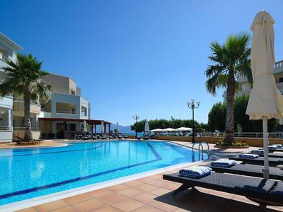 Moderner Außenpool mit Liegestühlen und Sonnenschirmen bei sonnigem Himmel.