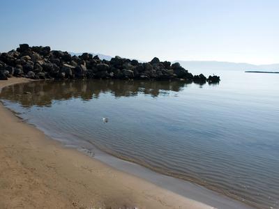 Helder water en zandstrand met rotsen langs de kust onder een heldere lucht