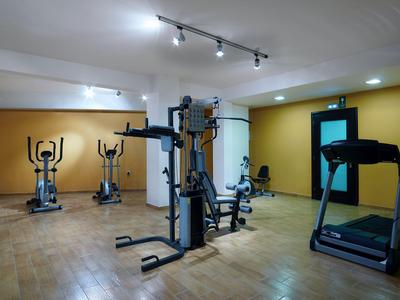 Moderner Fitnessraum mit Trainingsgeräten und Laufband in hellem Raum.