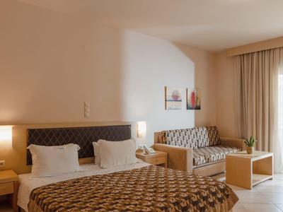 Gezellige hotelkamer met tweepersoonsbed, bank, nachtkastjes en natuurlijk licht.